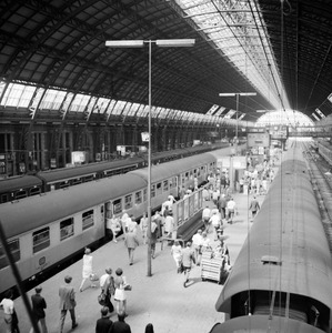 881970 Gezicht op de perrons onder de eerste perronkap van het N.S.-station Amsterdam C.S. te Amsterdam.